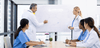 Group of medical professionals in a meeting with a whiteboard in a modern office setting.